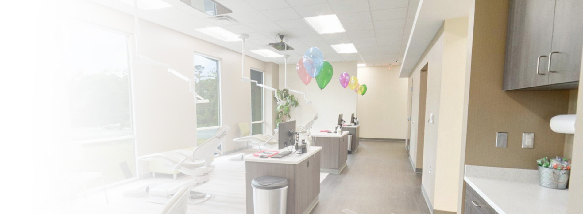 The image depicts an interior space that appears to be a modern office or reception area, with a clean and well-lit environment featuring a desk, chairs, a receptionist area, and a decorative balloon.
