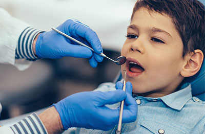 An image of a dental professional performing a procedure on a patient, with the patient seated in a chair and receiving treatment.