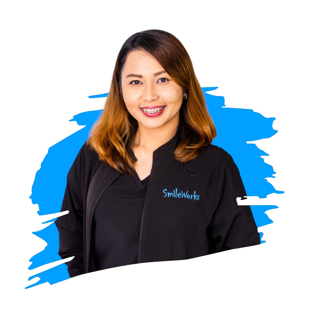 A woman in a black jacket with a name tag reading  SMILEWORKS  stands against a blue background.