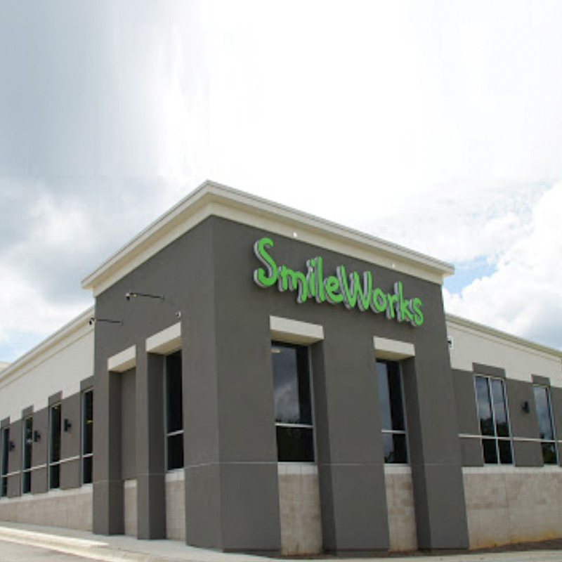 The image shows a building with a sign that reads  smileworks  on its facade, indicating it is a dental practice or clinic.