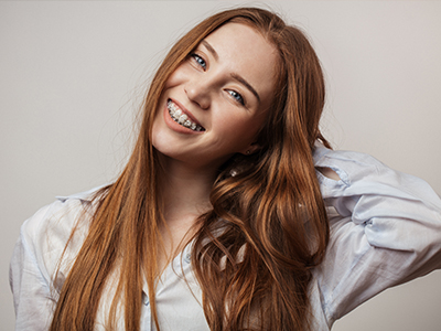 A young woman with long brown hair, smiling and looking to the side, against a neutral background.